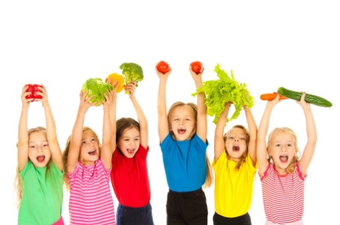 Bunt gekleidete Kinder halten verschiedene Gemüse hoch.